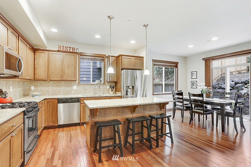 4733 Northeast 13th Place Renton, WA 98059 - Photo 2 of 20 a kitchen with stainless steel appliances granite countertop a stove top oven a sink dishwasher a dining table and chairs with wooden floor