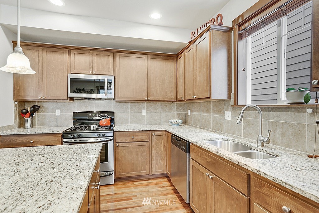 4733 Northeast 13th Place Renton, WA 98059 - Photo 4 of 20 a kitchen with a sink a stove a microwave and wooden cabinets