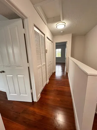 a view of a hallway with wooden floor and staircase