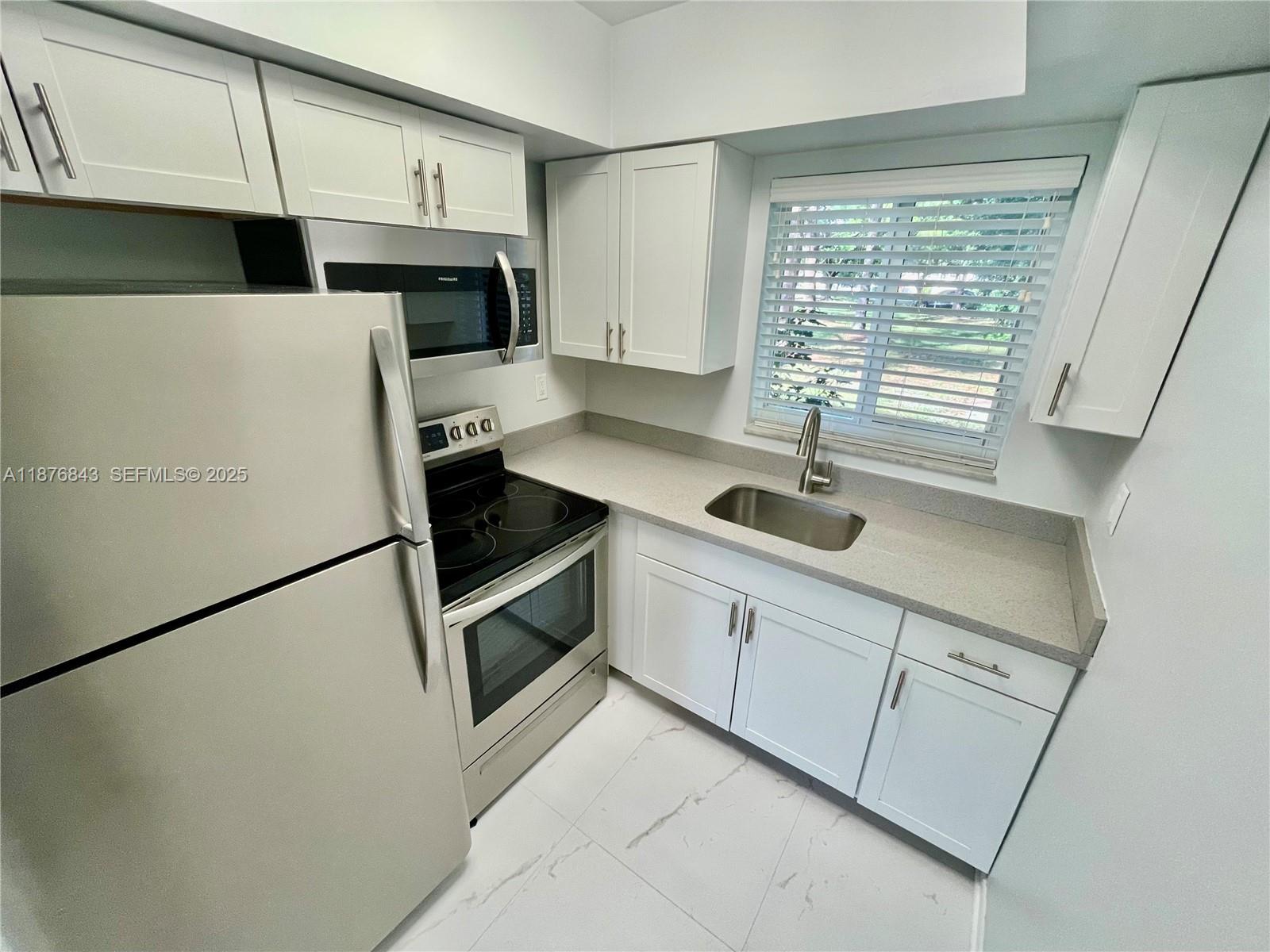 2616 Northeast 14th Avenue, Unit 2 Wilton Manors, FL 33334 - Photo 13 of 16 a kitchen with stainless steel appliances a refrigerator sink and microwave