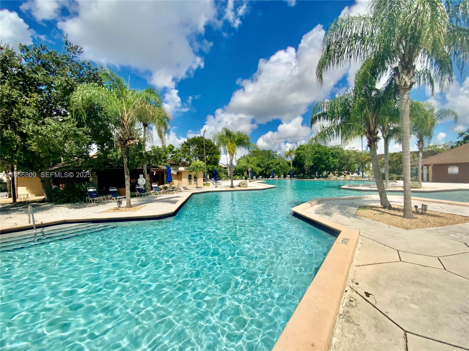 7024 Southwest 114th Place, Unit A52 Miami, FL 33173 - Photo 38 of 41 a view of swimming pool with lawn chairs plants and palm trees