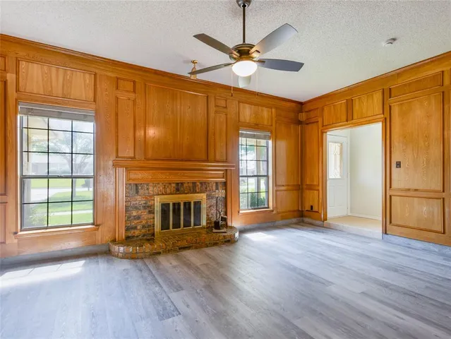 an empty room with wooden floor fireplace and windows