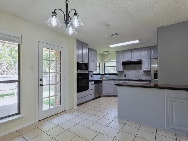 a large kitchen with granite countertop a large counter top space appliances and cabinets
