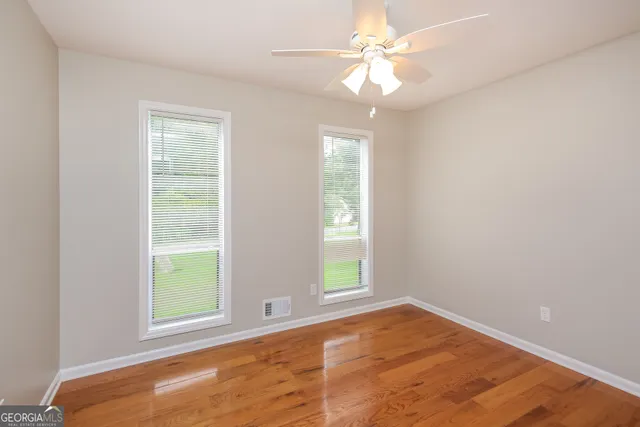 an empty room with windows and fan