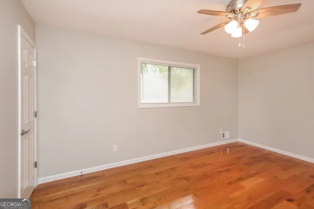 an empty room with a window and a chandelier fan