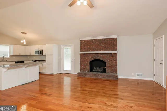 a view of kitchen and empty room with wooden floor