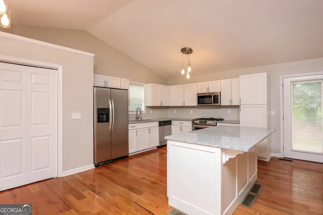 a kitchen that has a lot of white cabinets and wooden floor