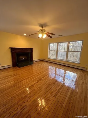 a view of an empty room with a window and wooden floor