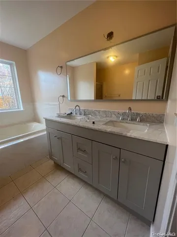 a spacious bathroom with a double vanity sink a mirror and a bathtub