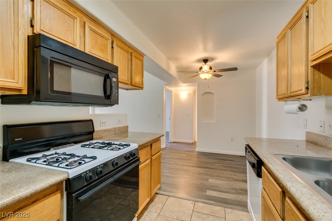 3318 North Decatur Boulevard, Unit 2138 Las Vegas, NV 89130 - Photo 27 of 40 Kitchen featuring gas range, black microwave, dishwasher, a ceiling fan, and light countertops