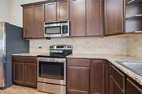 a kitchen with granite countertop cabinets stainless steel appliances and wooden cabinets