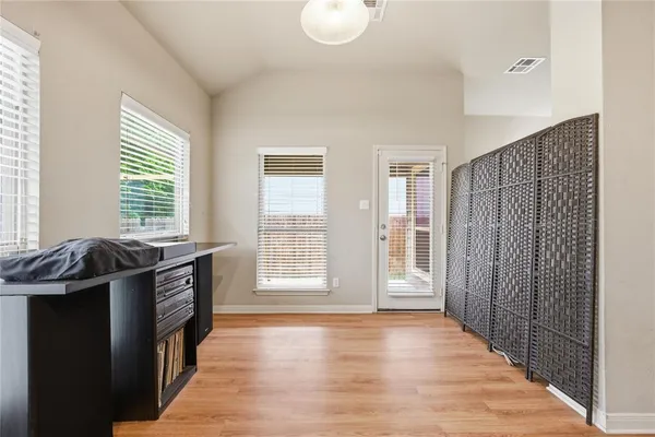 a view of an empty room with a kitchen and a window