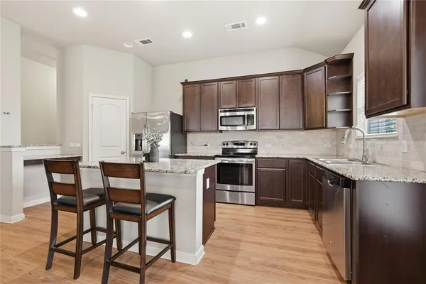 a kitchen with kitchen island granite countertop wooden cabinets and stainless steel appliances