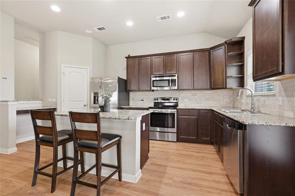 10808 Aurora Drive Waco, TX 76708 - Photo 10 of 23 a kitchen with kitchen island granite countertop wooden cabinets and stainless steel appliances