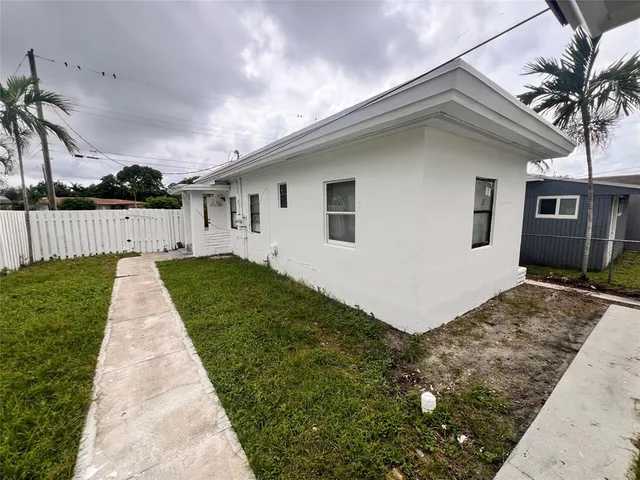 a front view of a house with a yard and potted plants