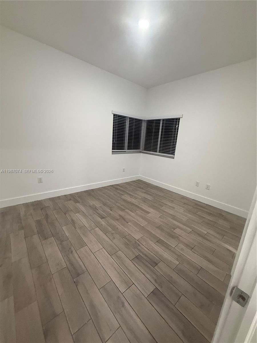 486 East 30th Street, Unit 202 Hialeah, FL 33013 - Photo 8 of 16 an empty room with wooden floor and windows
