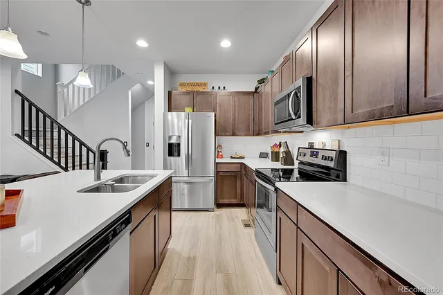 a kitchen with stainless steel appliances granite countertop refrigerator a sink dishwasher a refrigerator oven and white cabinets next to a window