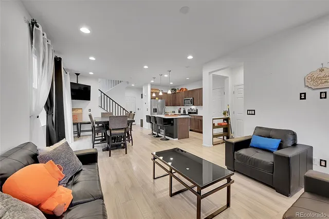 a living room with furniture kitchen view and a wooden floor