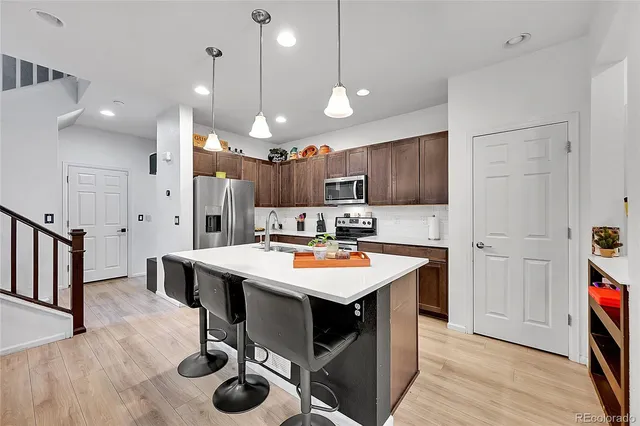 a kitchen with stainless steel appliances kitchen island a table chairs in it and wooden floors