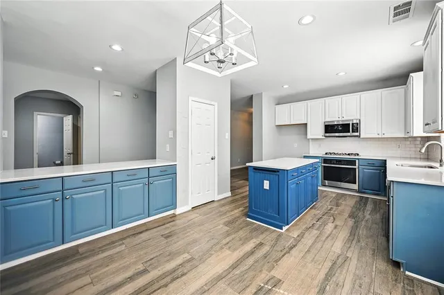 a kitchen with stainless steel appliances granite countertop a stove a sink dishwasher a refrigerator and a oven with wooden floor