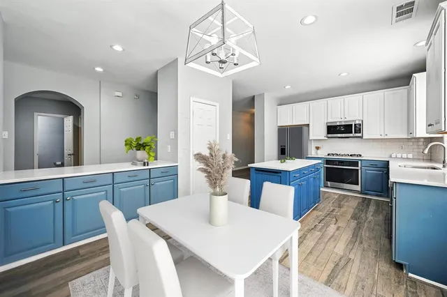 a open kitchen with stainless steel appliances granite countertop a stove a sink a refrigerator a microwave oven with a dining table and chairs