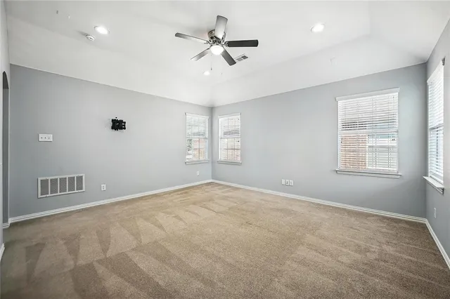 an empty room with windows and fan