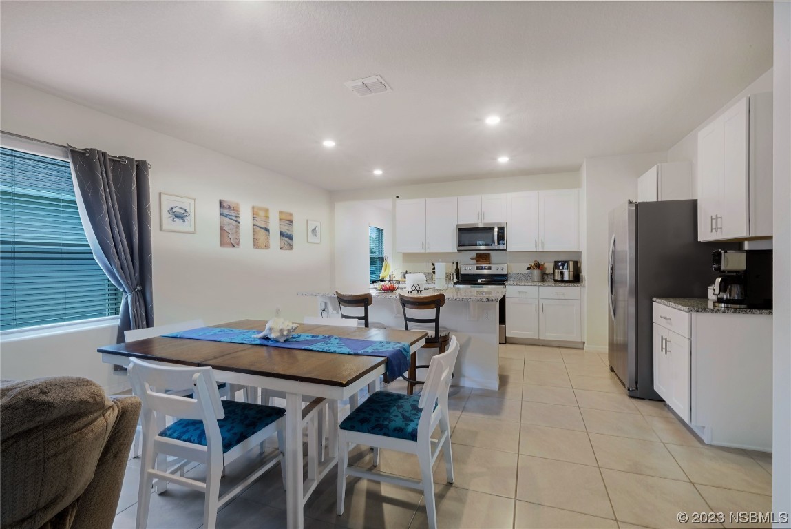 354 Camilla Road DeLand, FL 32724 - Photo 12 of 57 a kitchen with a dining table chairs refrigerator and microwave