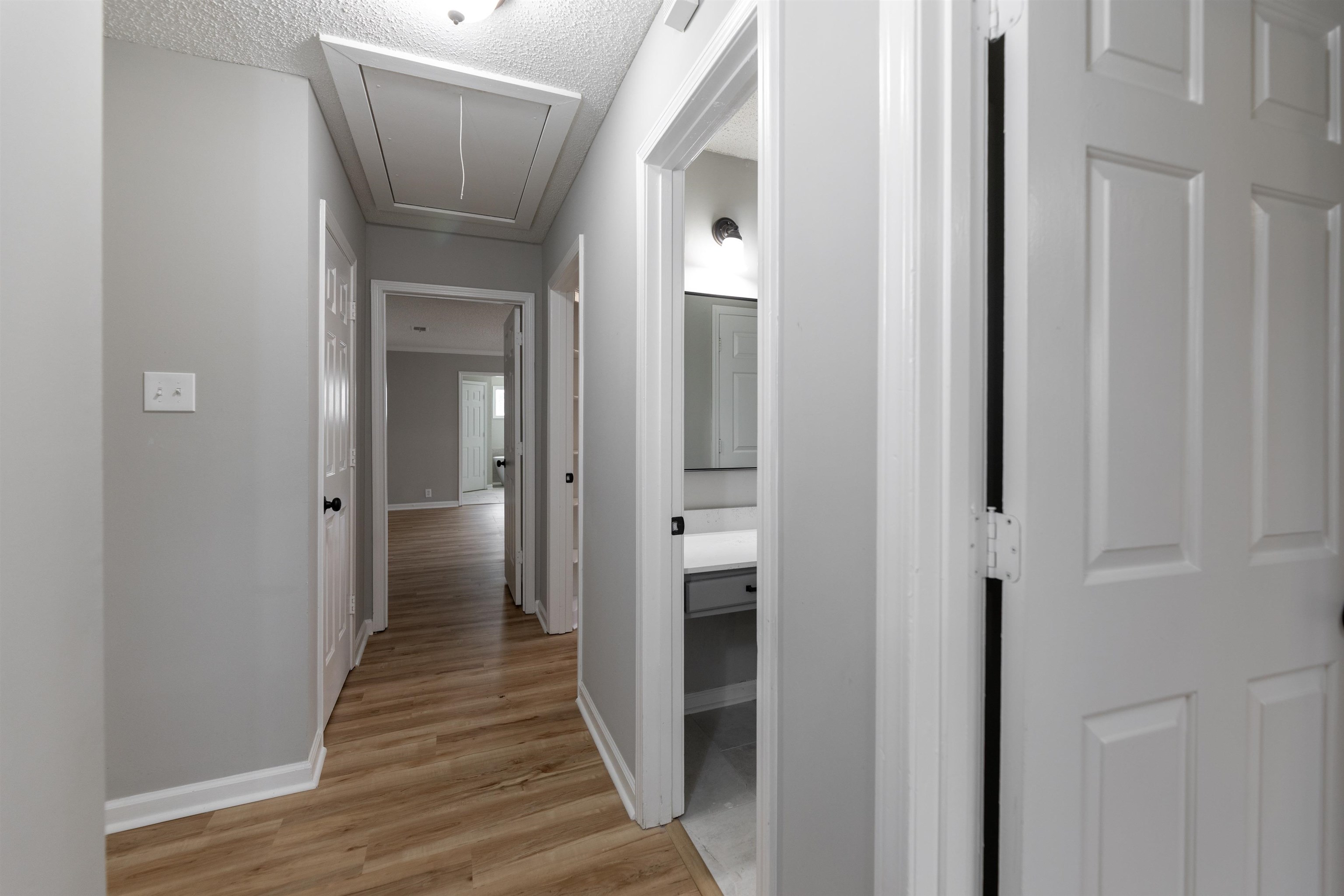 7421 Richmond Road Memphis, TN 38125 - Photo 18 of 39 Hallway featuring wood-finish flooring, light gray walls, white trim, and multiple doorways