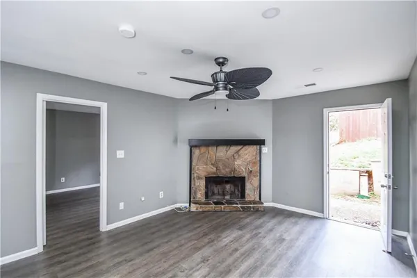 an empty room with wooden floor a fireplace and windows