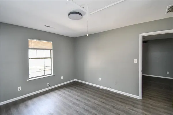 an empty room with wooden floor and windows