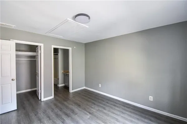 a view of an empty room with wooden floor and closet
