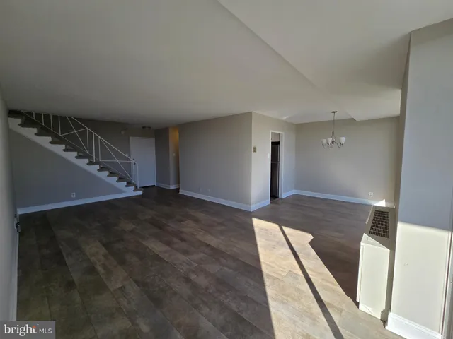 a view of a hallway to an empty room and wooden floor