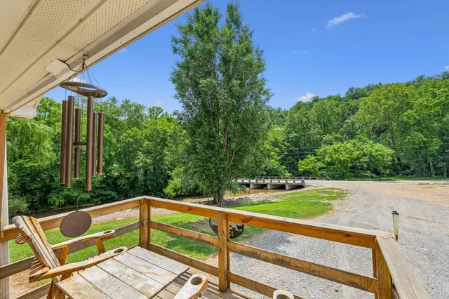 a kitchen with stainless steel appliances a stove a refrigerator a sink a dining table and chairs with wooden floor