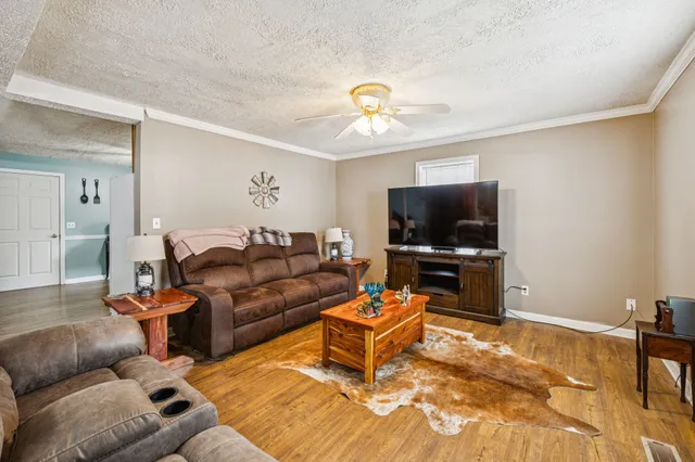 a kitchen with stainless steel appliances granite countertop a refrigerator a sink dishwasher a stove and white countertops with wooden floor