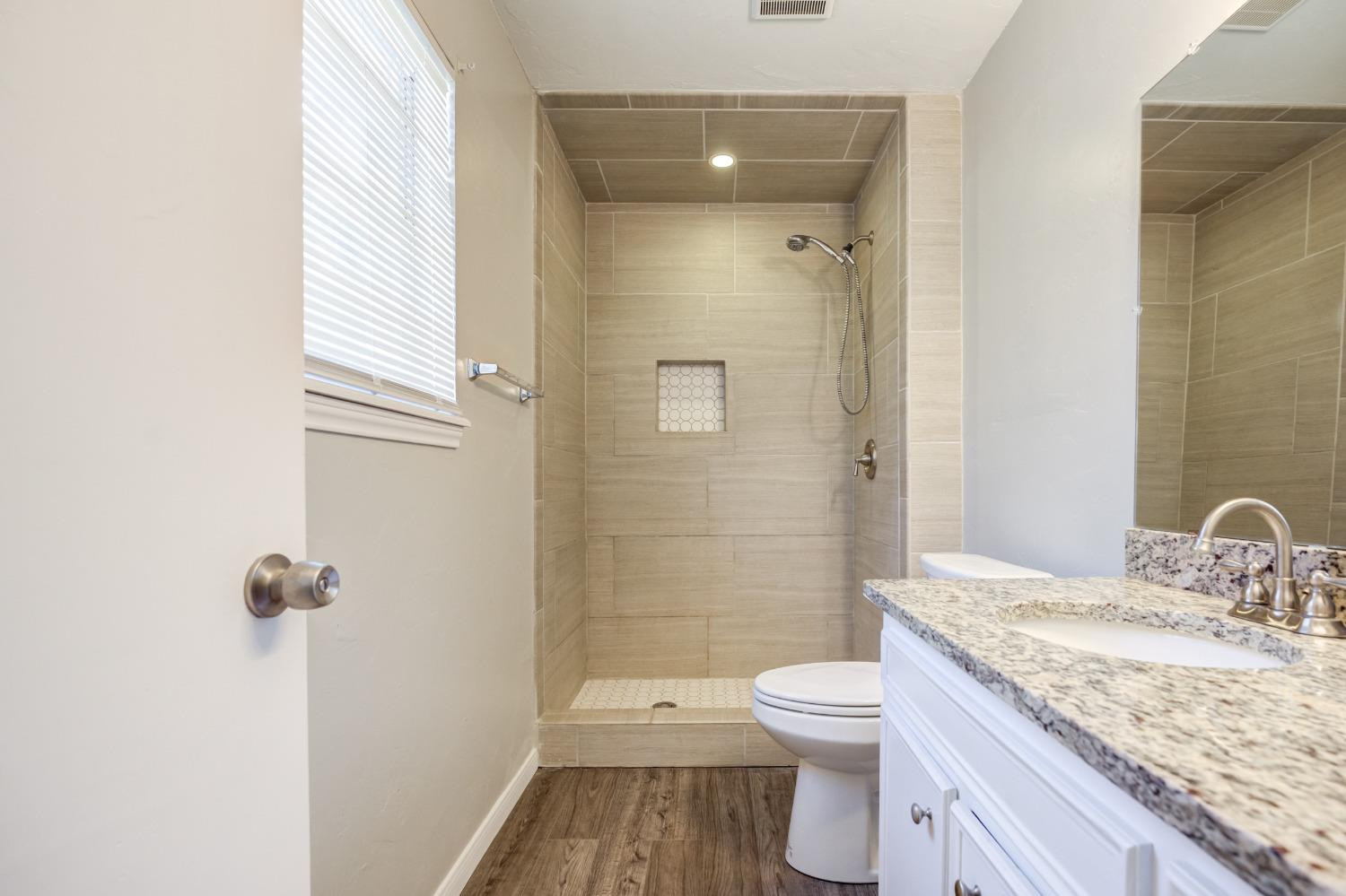2314 79th Street Lubbock, TX 79423 - Photo 12 of 33 a bathroom with a granite countertop toilet a sink and a mirror