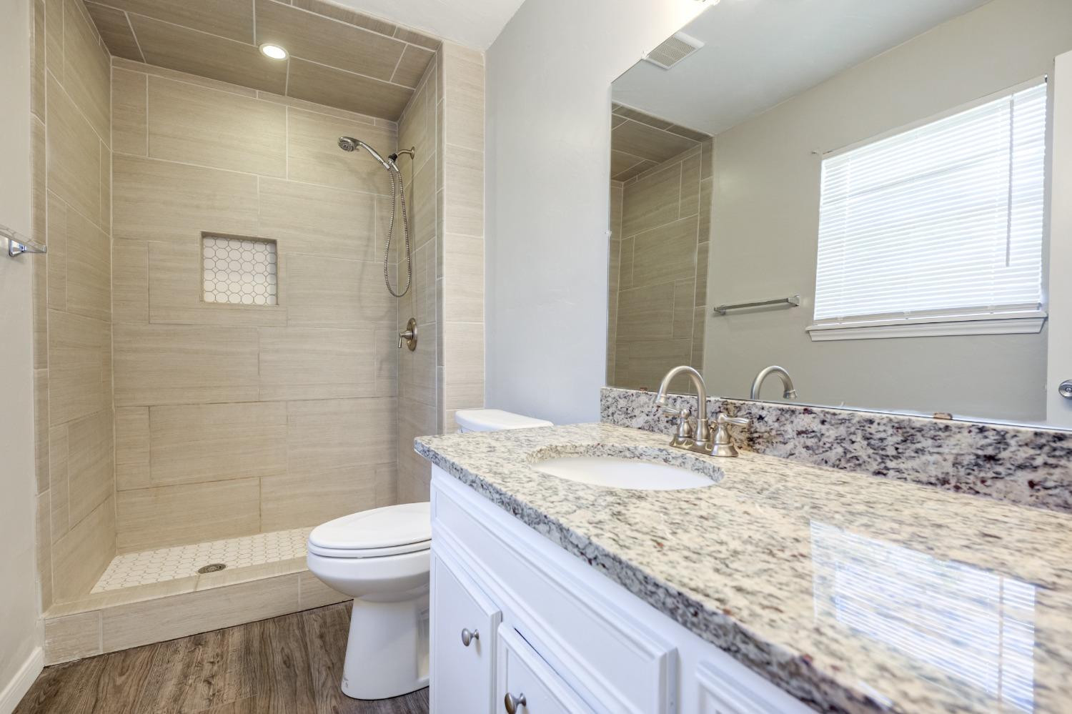 2314 79th Street Lubbock, TX 79423 - Photo 13 of 33 a bathroom with a granite countertop sink a toilet and shower