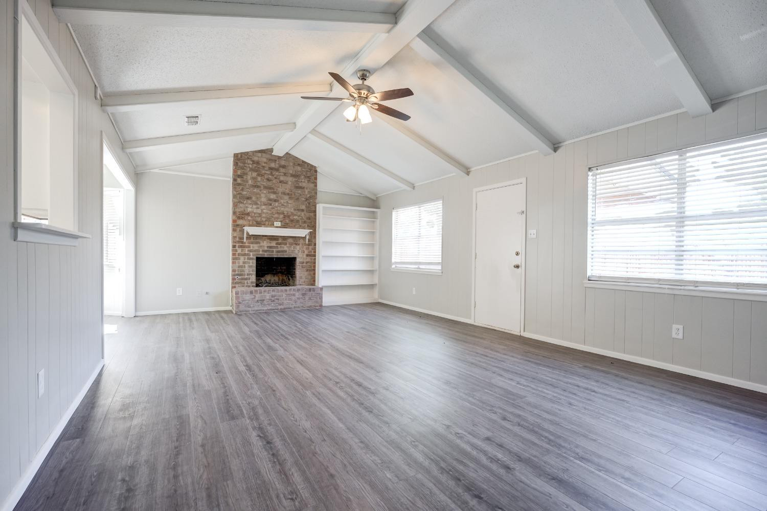 2314 79th Street Lubbock, TX 79423 - Photo 14 of 33 an empty room with wooden floor chandelier fan and windows