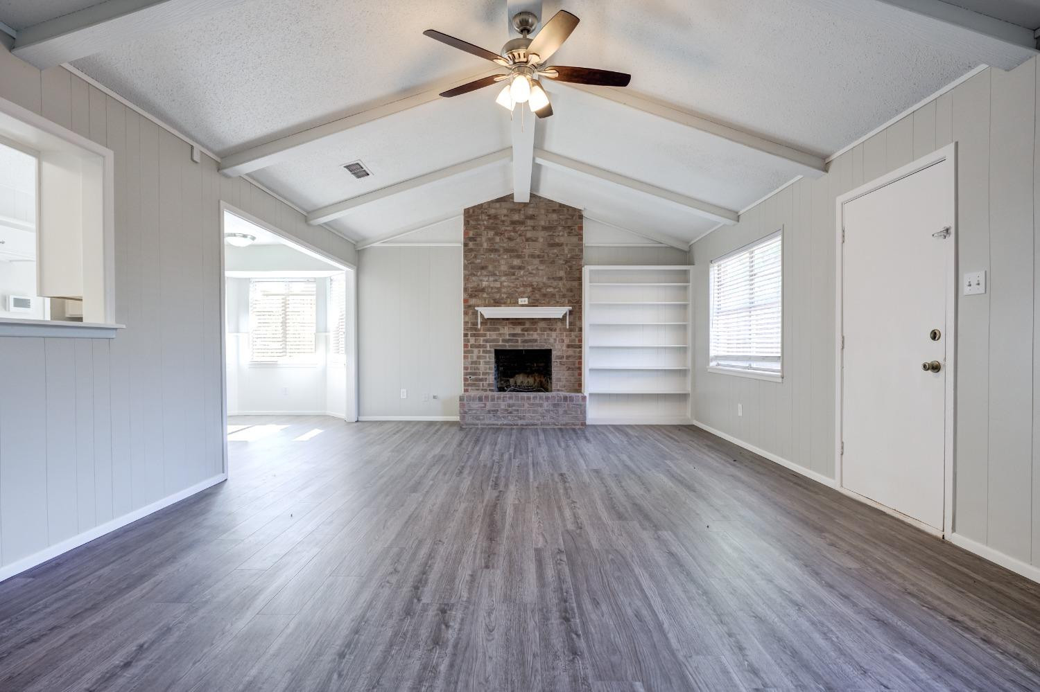 2314 79th Street Lubbock, TX 79423 - Photo 15 of 33 a view of an empty room with wooden floor fireplace and a window