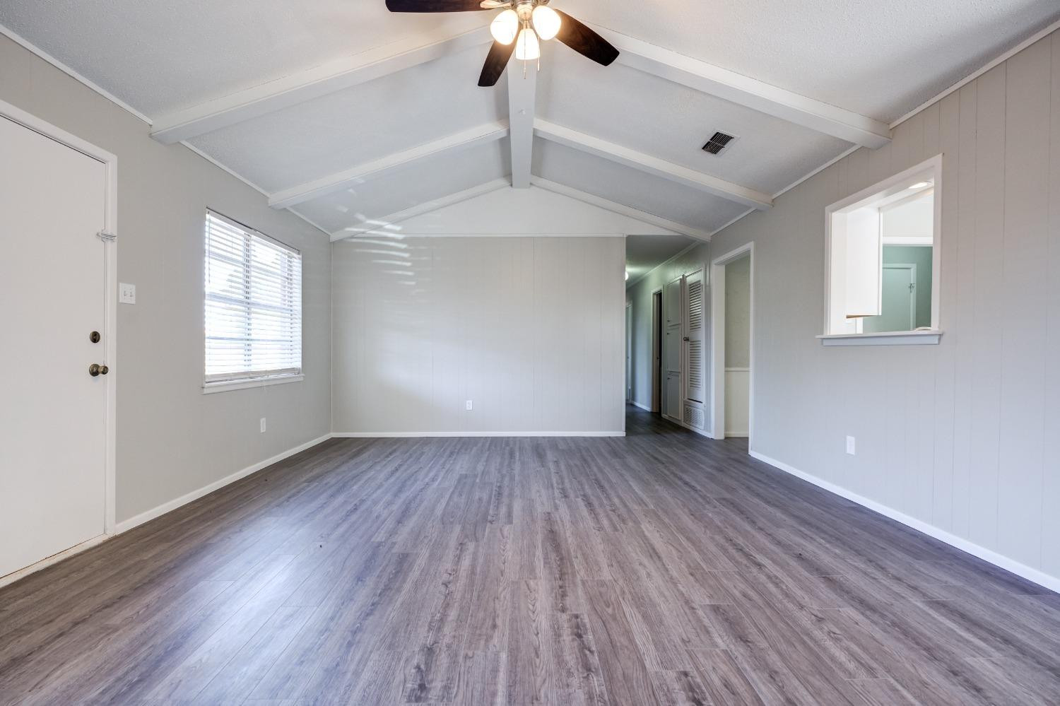 2314 79th Street Lubbock, TX 79423 - Photo 19 of 33 an empty room with wooden floor chandelier fan and windows