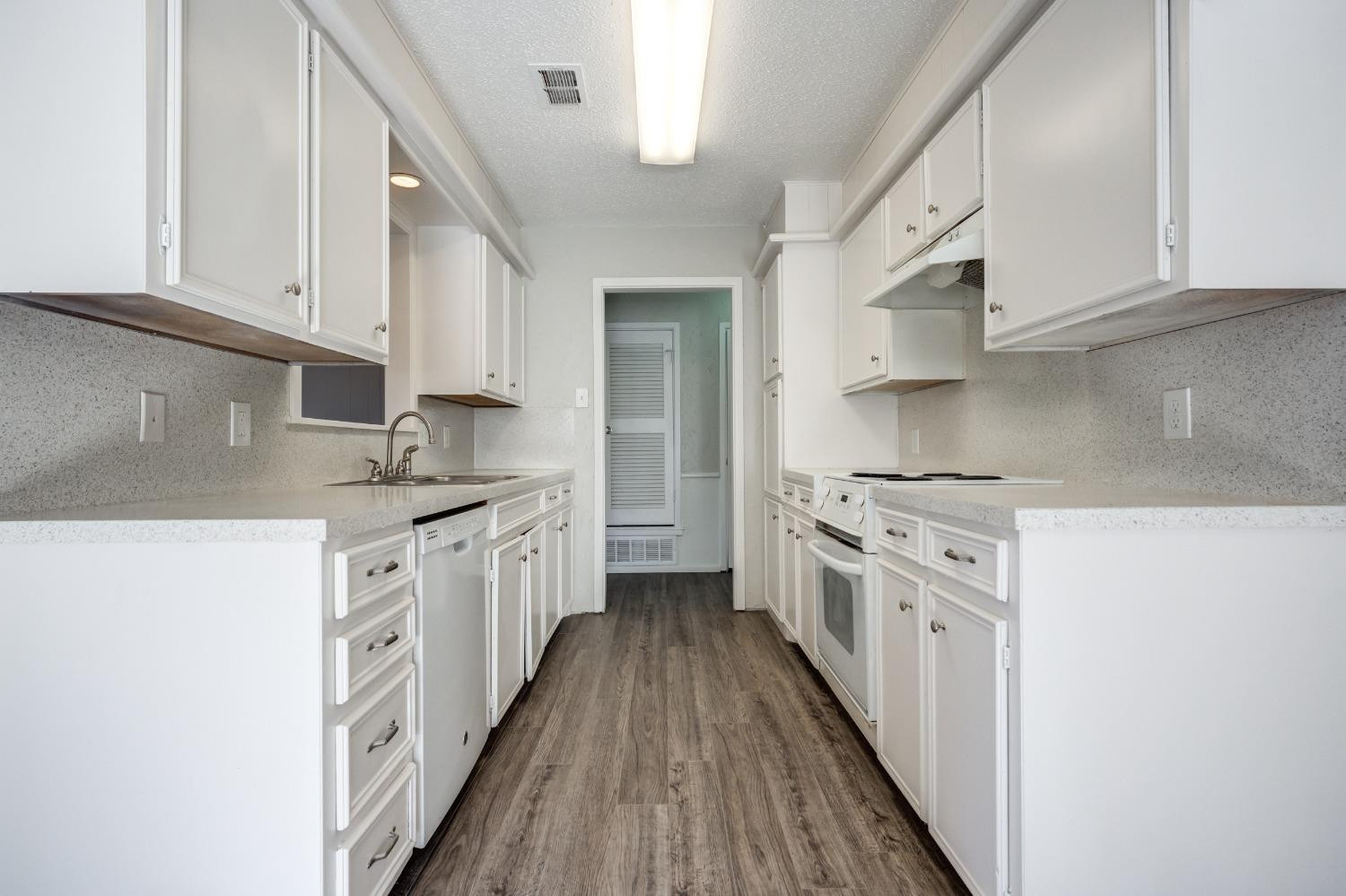 2314 79th Street Lubbock, TX 79423 - Photo 22 of 33 a kitchen with stainless steel appliances a stove top oven a sink a refrigerator white cabinets and wooden floor