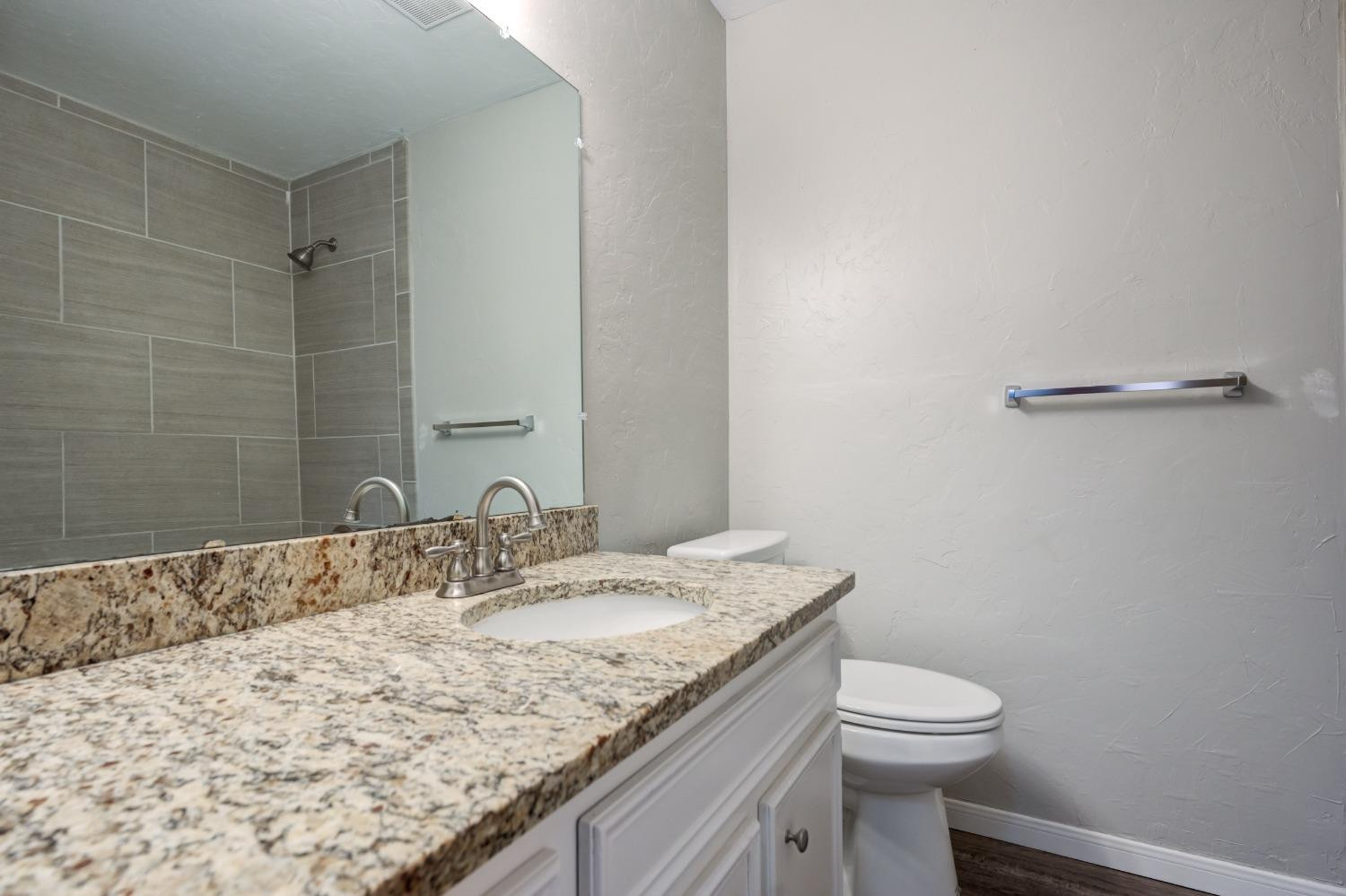 2314 79th Street Lubbock, TX 79423 - Photo 6 of 33 a bathroom with a granite countertop sink a toilet and a mirror