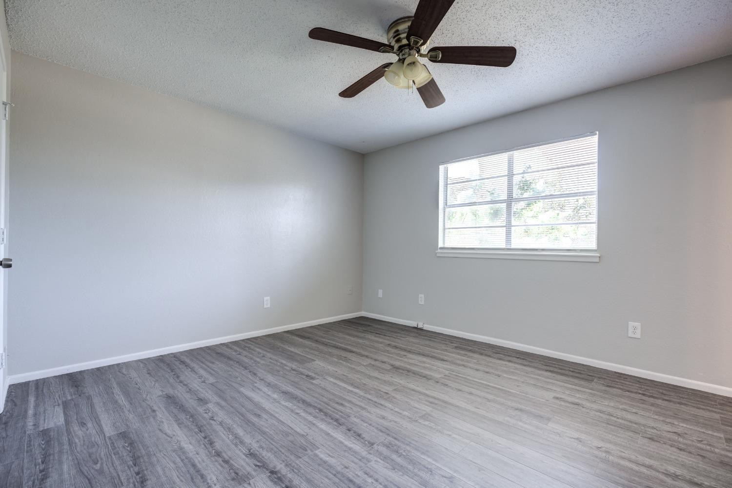2314 79th Street Lubbock, TX 79423 - Photo 10 of 33 an empty room with wooden floor ceiling fan and windows