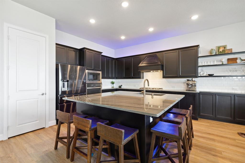18142 Lakefront Court Forney, TX 75126 - Photo 7 of 26 a kitchen with stainless steel appliances kitchen island granite countertop a kitchen island hardwood floor and chairs