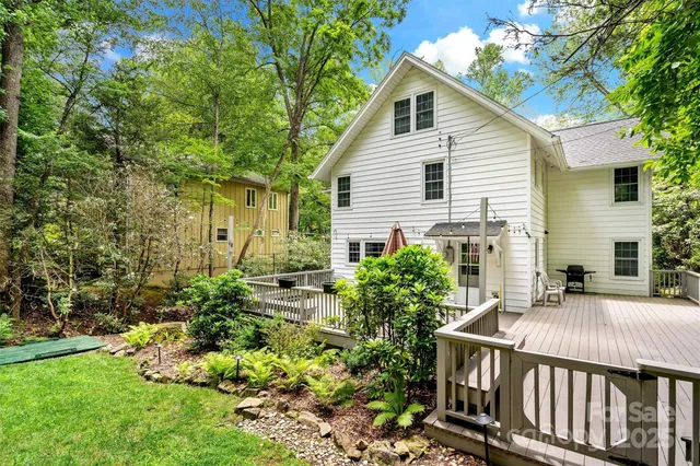 a view of barn house with a big yard plants and large trees