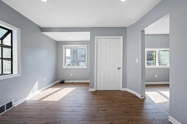 a view of an empty room with wooden floor and a window