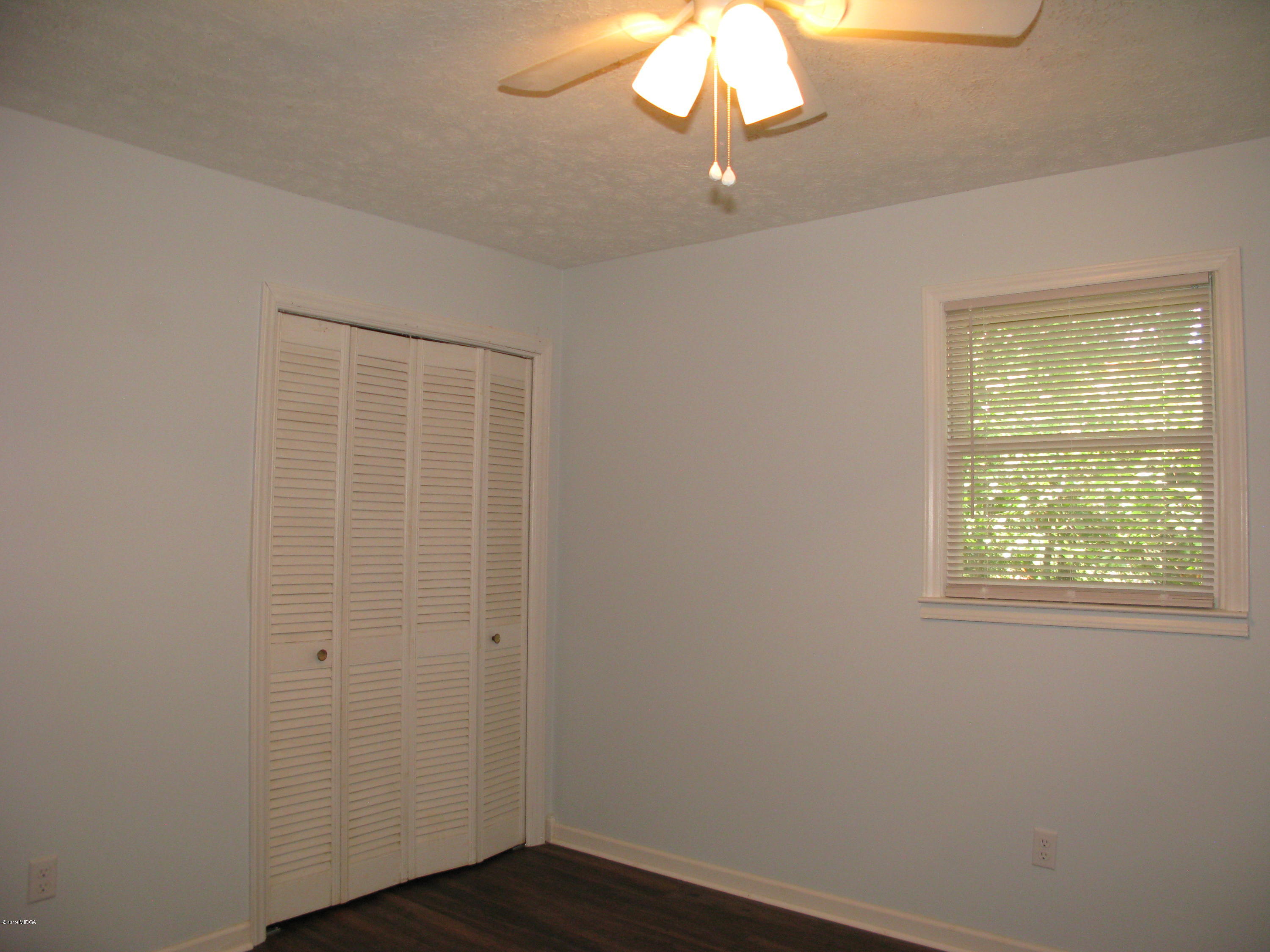 3812 Western Way Macon, GA 31216 - Photo 24 of 29 an empty room with a chandelier fan and wooden floor