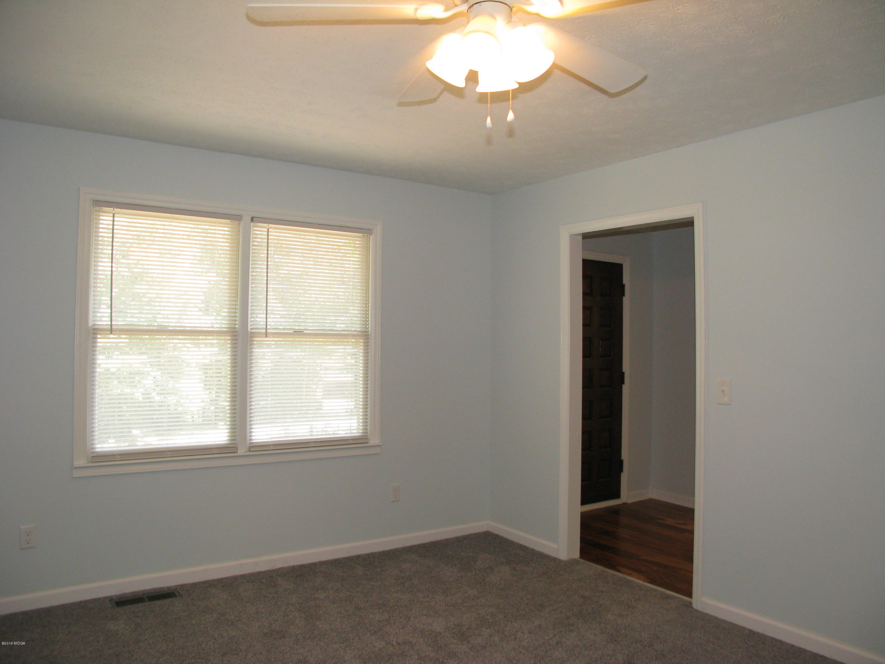 3812 Western Way Macon, GA 31216 - Photo 10 of 29 an empty room with a chandelier fan and windows