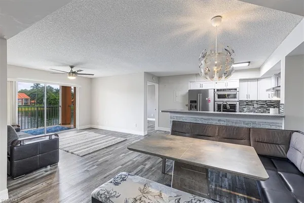 a kitchen with granite countertop kitchen island stainless steel appliances a dining table chairs sink and cabinets