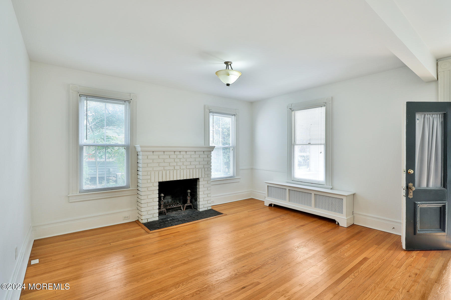 94 Branch Avenue Red Bank, NJ 07701 - Photo 3 of 21 an empty room with windows fireplace and wooden floor