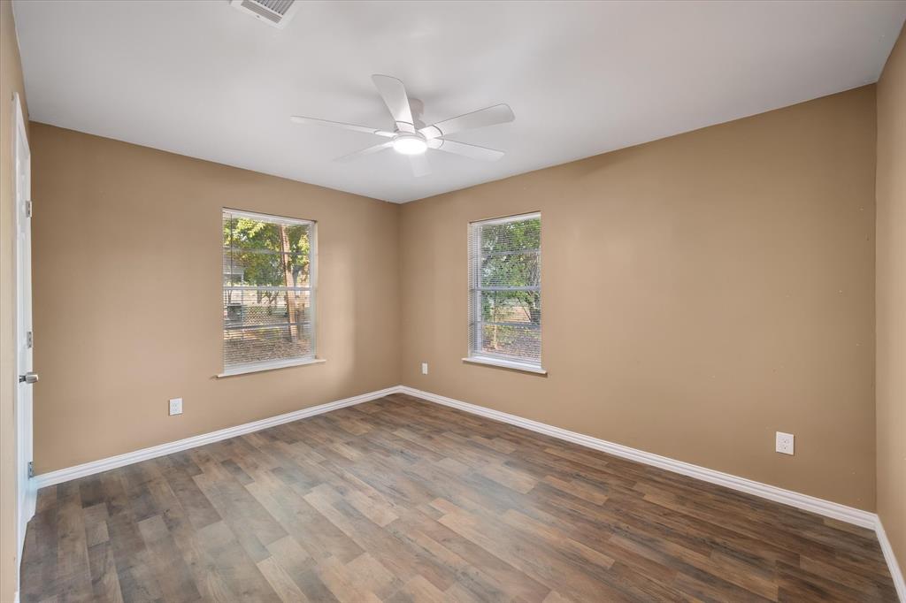3400 Emhouse Road Corsicana, TX 75110 - Photo 30 of 34 Room featuring wood-finish flooring, two windows, a ceiling fan with integrated lighting, and a neutral wall color